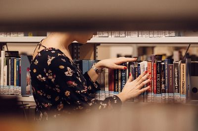 Photo d'un fille qui cherche un livre dans un rayon d'une bibliothèque